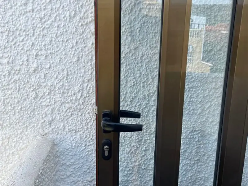 Puerta de aluminio con manilla y cerradura negras